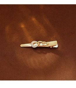 Detail of golden chain hair clip with sparkling rhinestones on textured brown surface