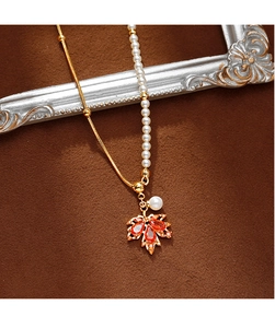 Détail du pendentif feuille d'érable avec gemme orange et collier de perles