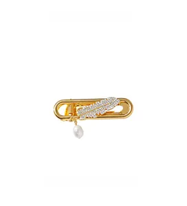 Detail of golden feather hair clip featuring sparkling zircons and a freshwater pearl