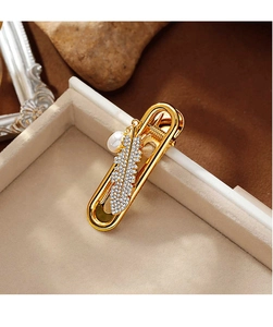 Detail of golden feather hair clip with sparkling zircons and a white freshwater pearl