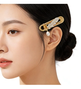 Detail of gold paperclip hair clip with rhinestone feather and drop pearl on model