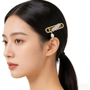 Elegant gold feather hair clip with sparkling crystals and a white teardrop pearl