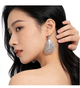 Macro view of oversized silver mesh leaf earrings with intricate metal镂空 detail