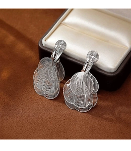 Detailed macro view of silver layered leaf tassel earrings on a brown velvet background