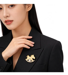 Détail d'une broche cheval dorée avec perle et zircon sur un blazer noir élégant