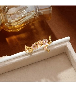 Vue macro d'une élégante broche fleur dorée avec émail rose sur un coffret à bijoux