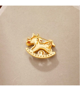 Gros plan d'une broche poney dorée ornée de perles blanches et de zircons cubiques