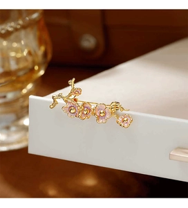 Vue macro d'une broche fleur de prunier en émail rose avec détails dorés élégants