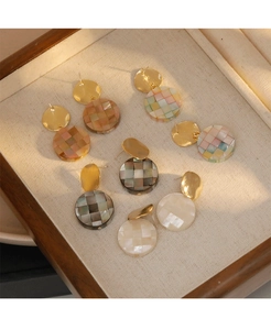 Gros plan de boucles d'oreilles mosaïque colorées dans un plateau à bijoux en lin