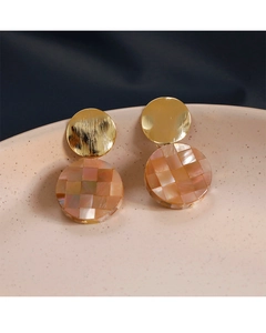 Détail de boucles d'oreilles mosaïque rose et orange sur une assiette en porcelaine