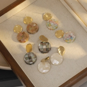 Parure de boucles d'oreilles mosaïque en damier dans un présentoir à bijoux en bois