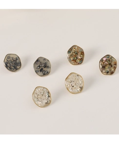 Dettaglio di orecchini geometrici con intarsi in conchiglia e bordo metallico