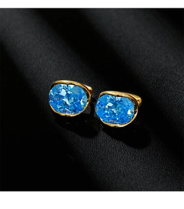 Macro detail of oval blue zircon earrings set in elegant gold plated metal frames