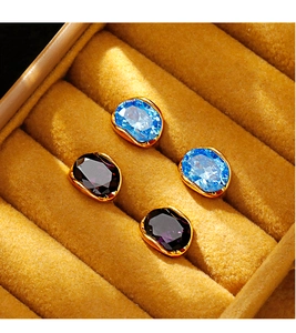 Detail of blue and purple oval zircon stud earrings with gold plating on velvet