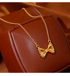 Detail van een gouden farfalle-pasta ketting op een luxe bruine lederen displaystand