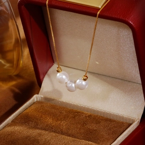 Elegante collar de oro con tres perlas blancas en una caja de regalo de lujo roja