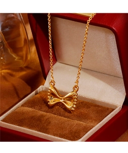 Detailopname van een gepolijste gouden strikhanger in een rood fluwelen juwelendoosje