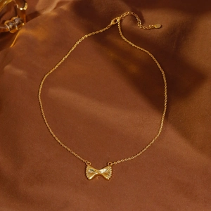 Elegante gouden strik ketting op bruin fluweel met verfijnde vintage uitstraling