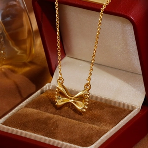 Elegante gouden strik hanger ketting gepresenteerd in een luxe rode fluwelen doosje