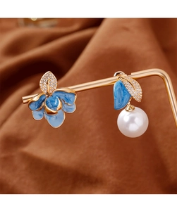 Détail de boucles d'oreilles émaillées bleues asymétriques avec perle sur support