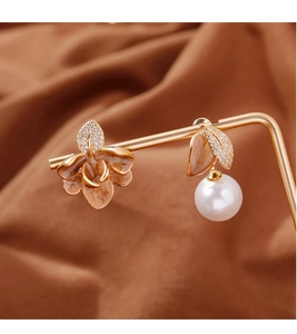 Détail de boucles d'oreilles asymétriques en émail avec perles sur support doré