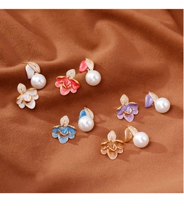 Vue à plat de boucles d'oreilles fleurs en émail coloré avec perles sur daim marron