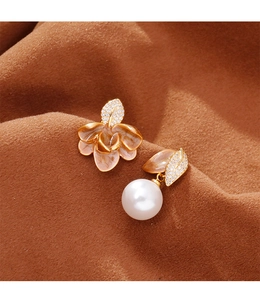 Détail macro de boucles d'oreilles asymétriques en émail avec motifs feuilles et perles