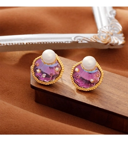 Detail van elegante waaiervormige gouden oorbellen met paars hars en parels