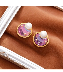 Macro-opname van vintage schelpoorbellen met paars kristal, parel en gouden details