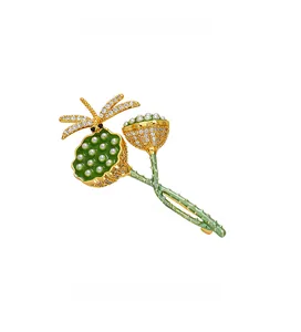 Nahaufnahme der Lotus-Libelle-Brosche mit grünem Emaille und weißen Kristallen