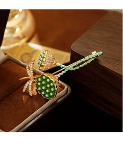 Makro-Detail der eleganten Lotuskapsel-Brosche mit grünem Emaille und Gold-Finish