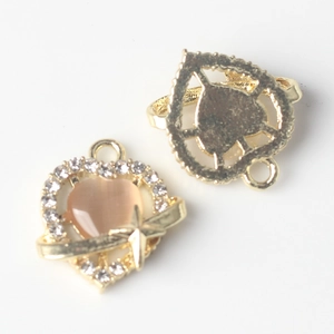 Close-up of gold heart charms with pink cat-eye stone and sparkling rhinestones