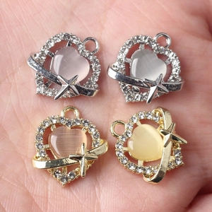 DIY heart pendants with cat-eye stones and rhinestones held in hand for jewelry making