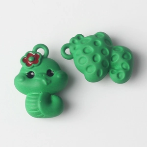 Macro detail of cute green snake charms with red flower and textured back for DIY jewelry