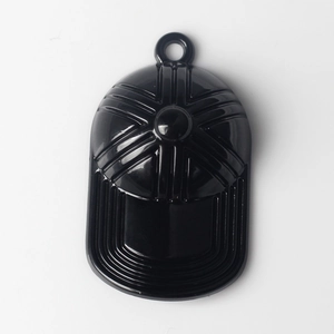 Macro shot of black baseball cap pendant with embossed sunburst texture and top loop