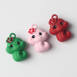 Detailed close-up of colorful cartoon snake pendants with heart eyes and floral head decor