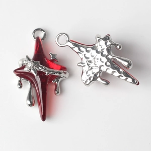 Detailed macro view of star-shaped cross charms with red resin and silver metal drips