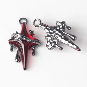 Macro shot of dark silver star pendants with red resin inlay and crystal accents