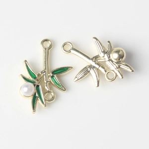 Macro detail of gold bamboo leaf pendant with green enamel and a white inlaid pearl