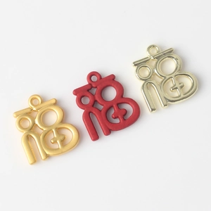 Detail of alloy Fu character pendants in matte gold, red lacquer and glossy gold finishes