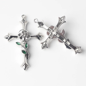Vue détaillée du pendentif croix gothique avec rose en relief et détails d'émail vert