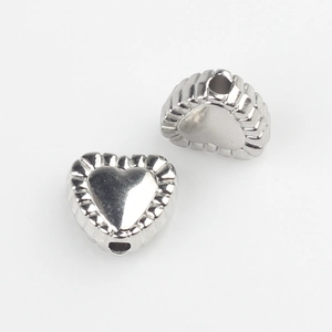 Detailed macro view of heart shaped silver alloy beads with textured scalloped edges
