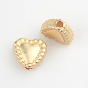 Macro detail of matte gold heart beads with serrated edges for DIY jewelry making