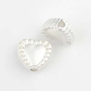Macro detail of silver heart-shaped alloy beads with embossed texture for DIY jewelry making