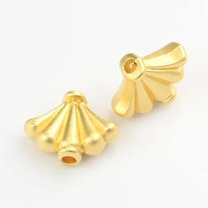 Close-up of golden fan-shaped alloy beads with matte texture and threading holes