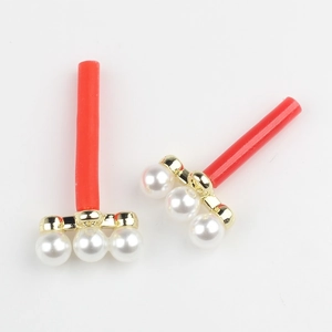 Vue détaillée d'accessoires d'oreilles rouges avec base dorée et trois perles blanches
