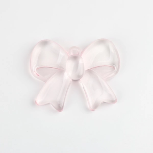 Detail of a translucent pink resin bow pendant with top hole for DIY jewelry making