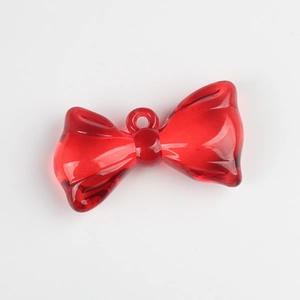 Macro view of transparent red resin bow pendant with gold hanging loop for DIY jewelry