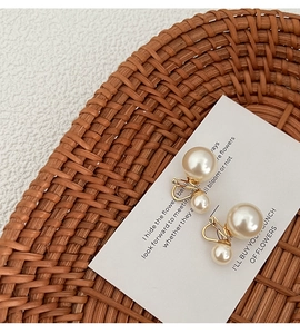 Dettaglio orecchini a clip con perle vintage su cartoncino in un cesto di vimini
