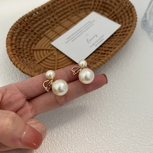 Orecchini a doppia perla a clip dorati in stile vintage, mostrati sulla mano